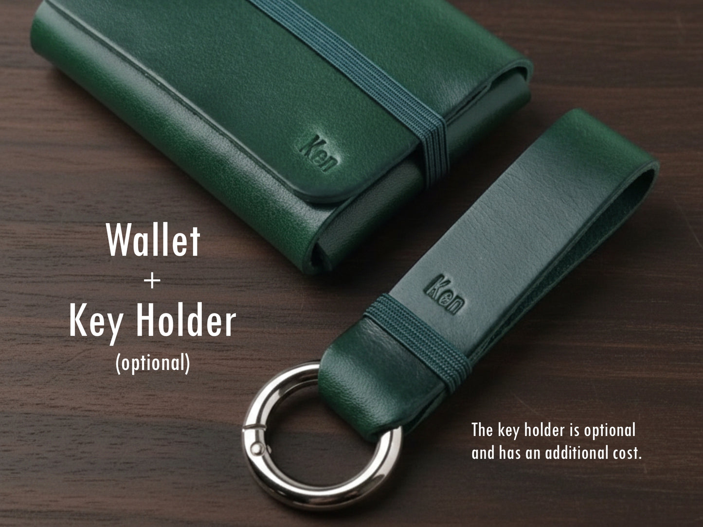 Carteira em couro alpine green com elástico verde sobre fundo de madeira escura, acompanhado de um porta-chaves combinando. No canto inferior direito, um aviso indica que o porta-chaves é opcional e possui custo adicional.